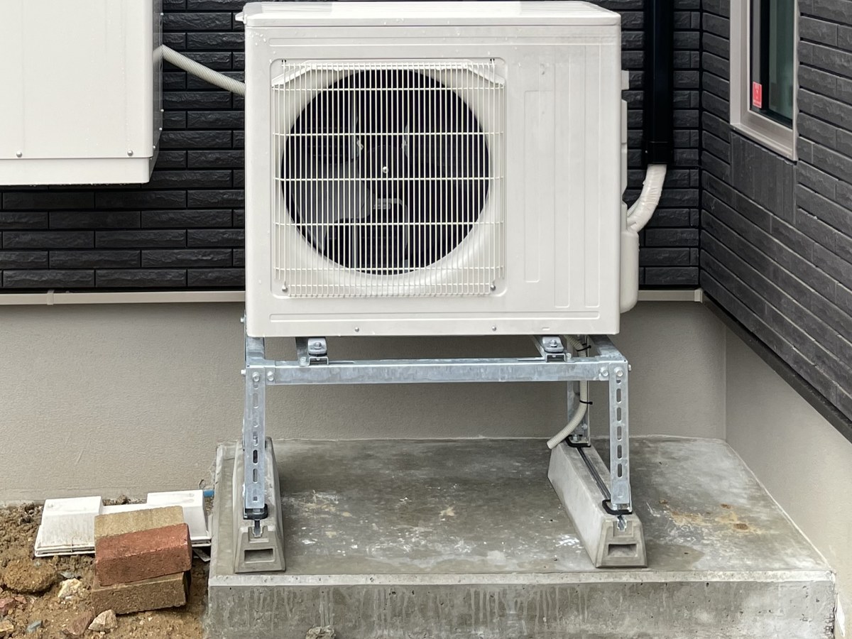 コンクリートベースの上に架台を置いて設置された室外機